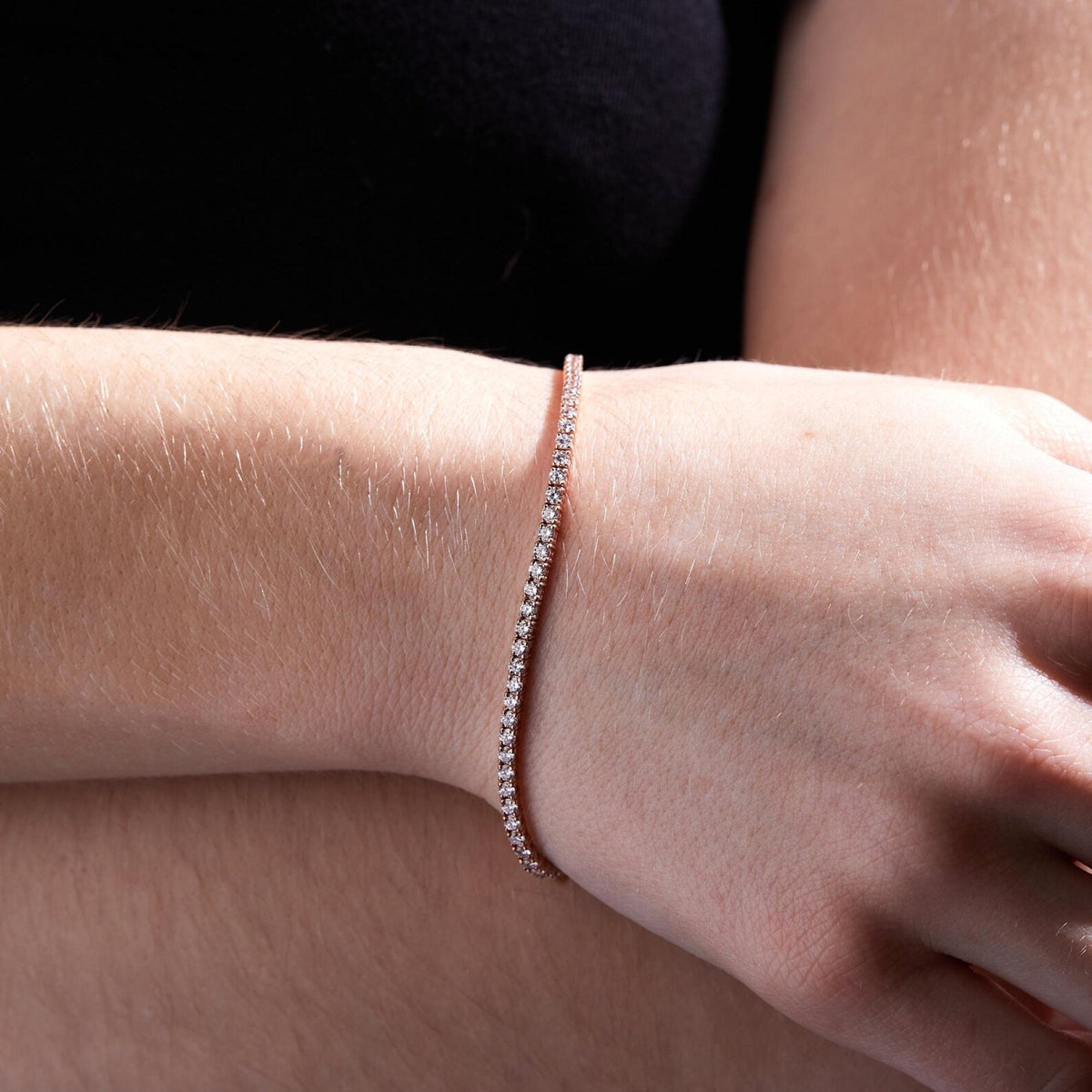 close-up of a wrist wearing a delicate bracelet on a plain background