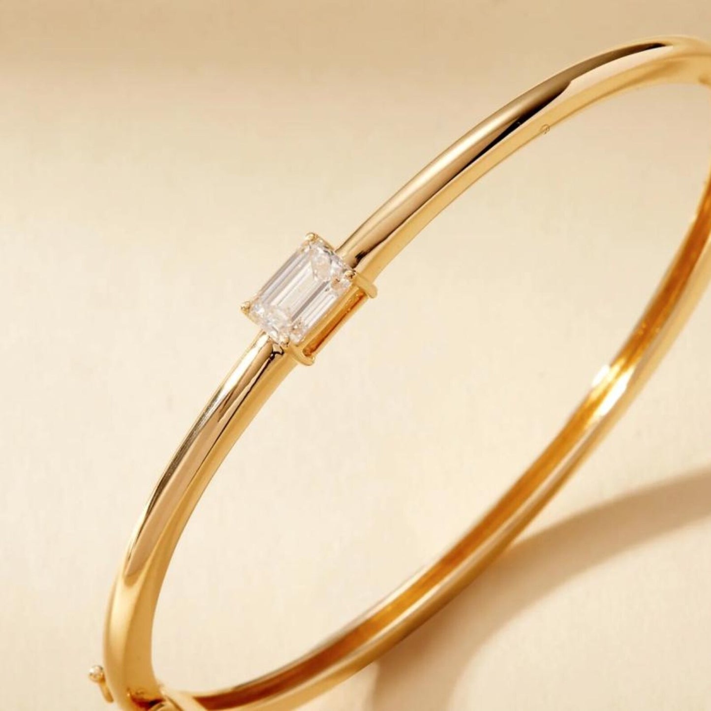 gold bracelet with a diamond on a beige