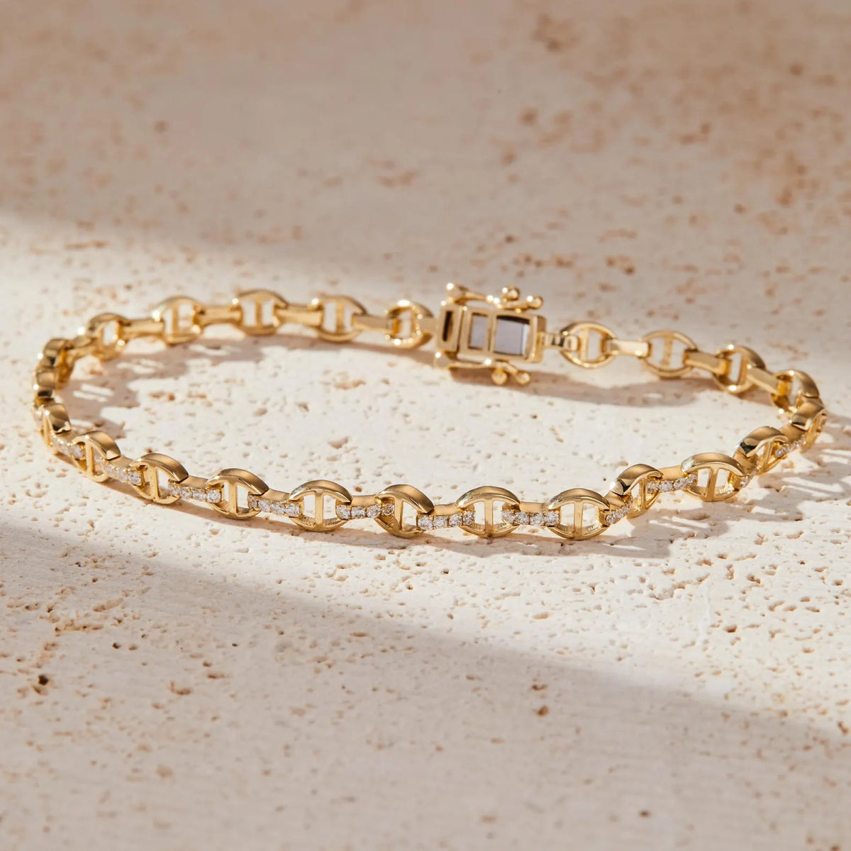 gold bracelet with a diamond on a beige