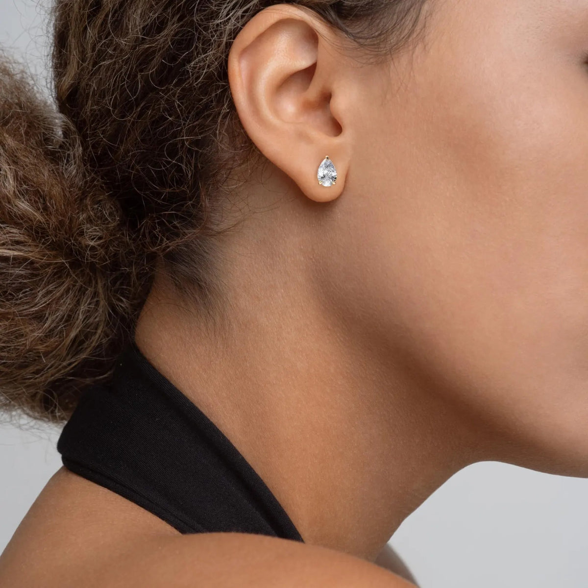 close-up of a person wearing a diamond earring on a neutral