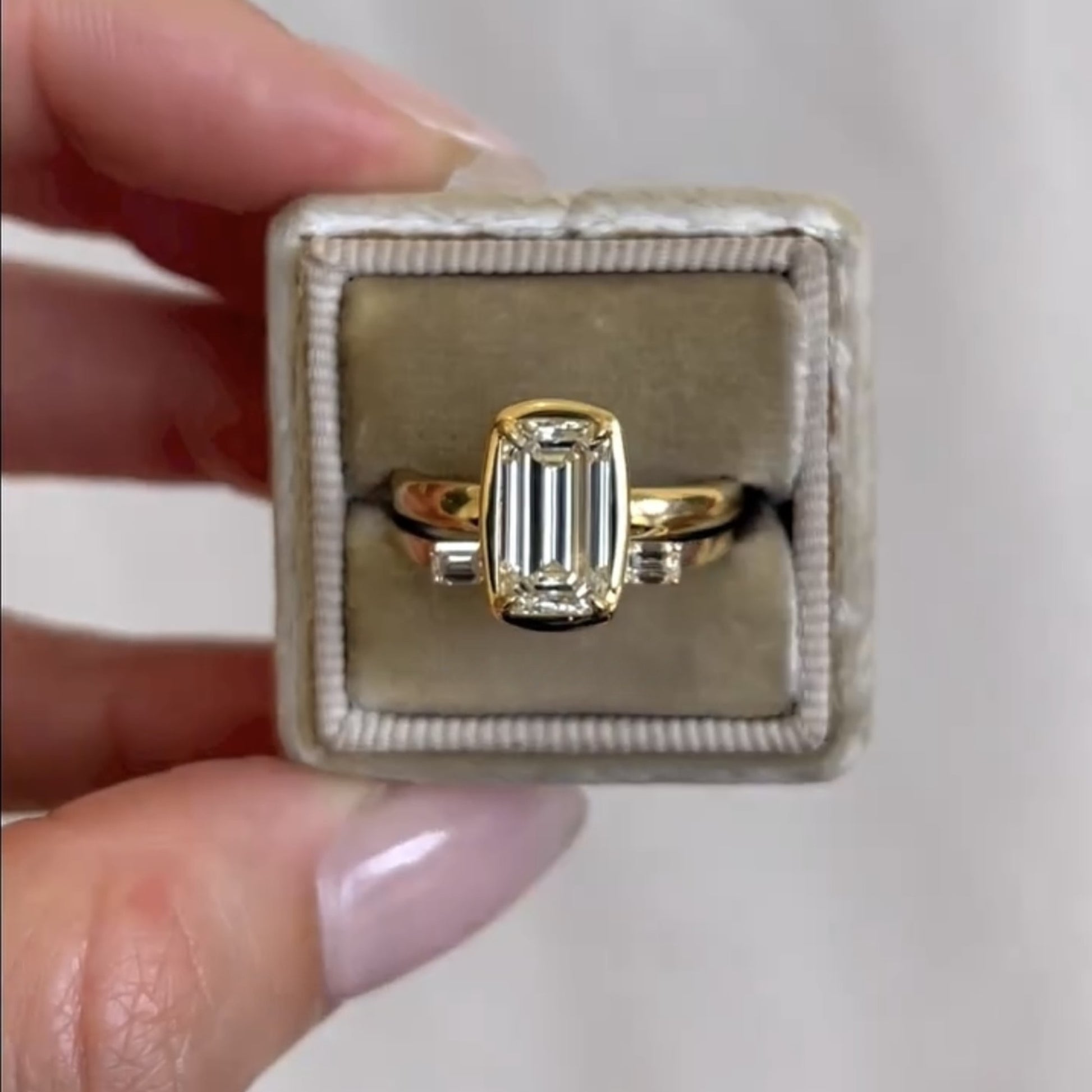 Gold ring with a diamond in a jewelry box held by a hand