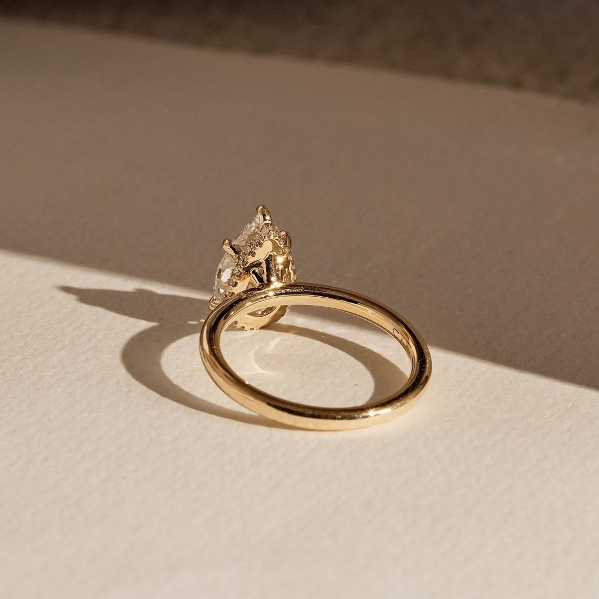 Gold ring with a diamond on a beige surface