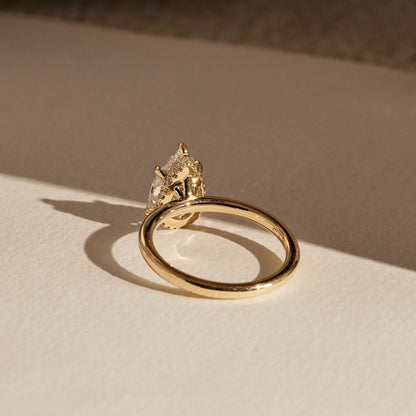 Gold ring with a diamond on a beige surface