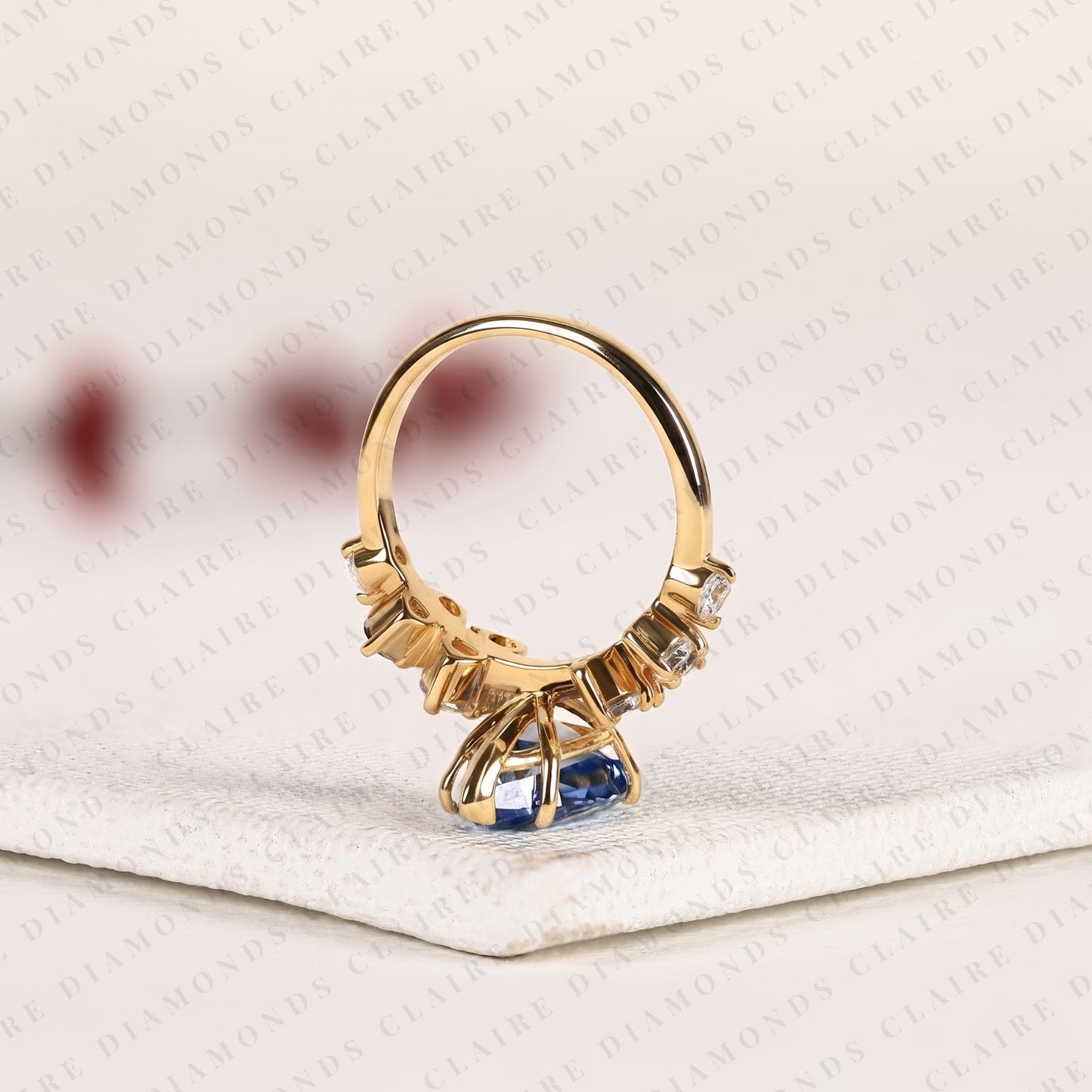 pear cut blue lab grown engagement ring, round diamond floral side stones, yellow gold nature-inspired bridal ring