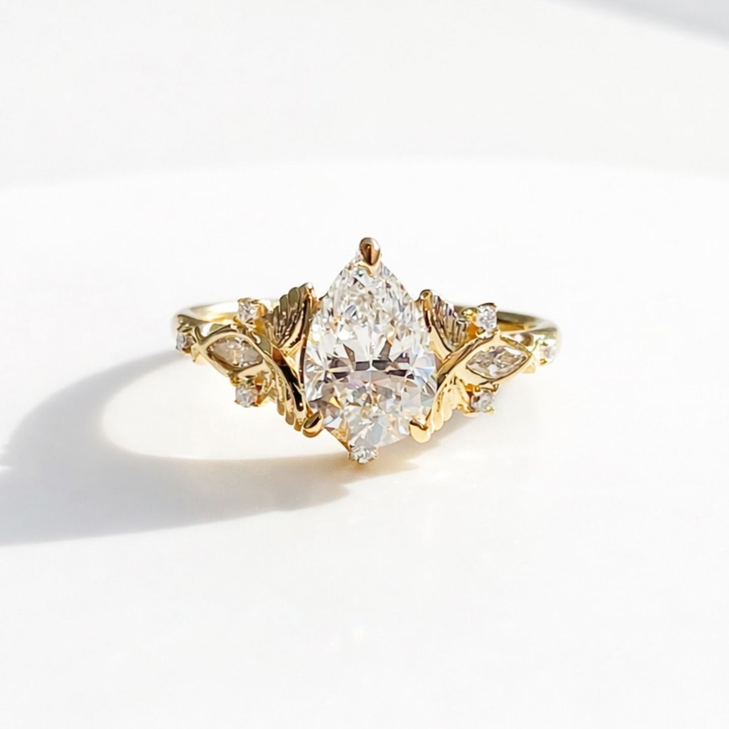vintage inspired pear cut moissanite diamond engagement ring with floral leaf side accents in solid gold