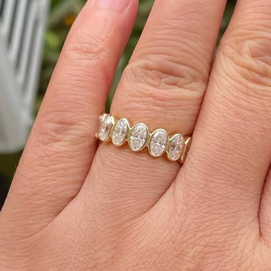 Hand wearing a gold ring with diamonds against a blurred 