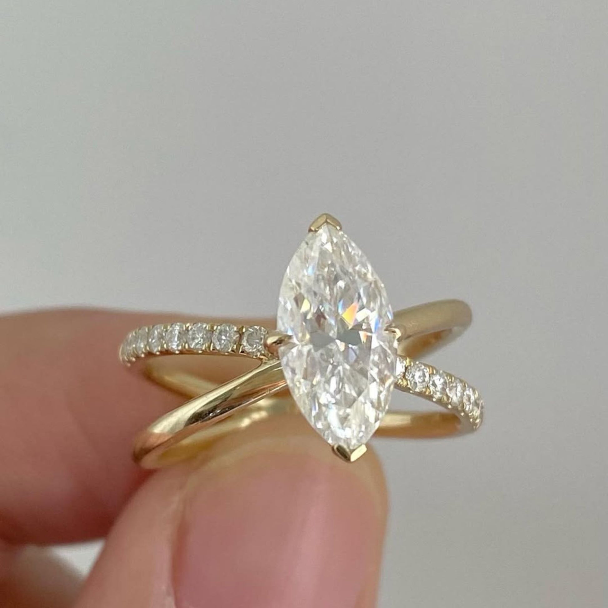 Gold ring with a large diamond held between fingers against a neutral