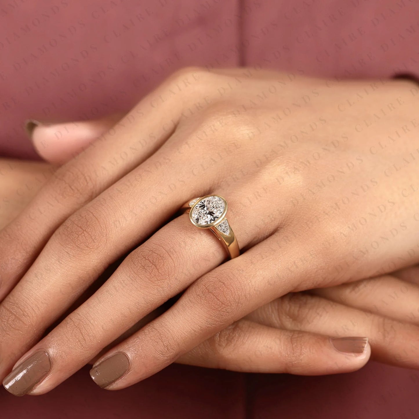 oval cut moissanite diamond engagement ring | bezel set gold ring with trillion side stones | modern luxury bridal ring