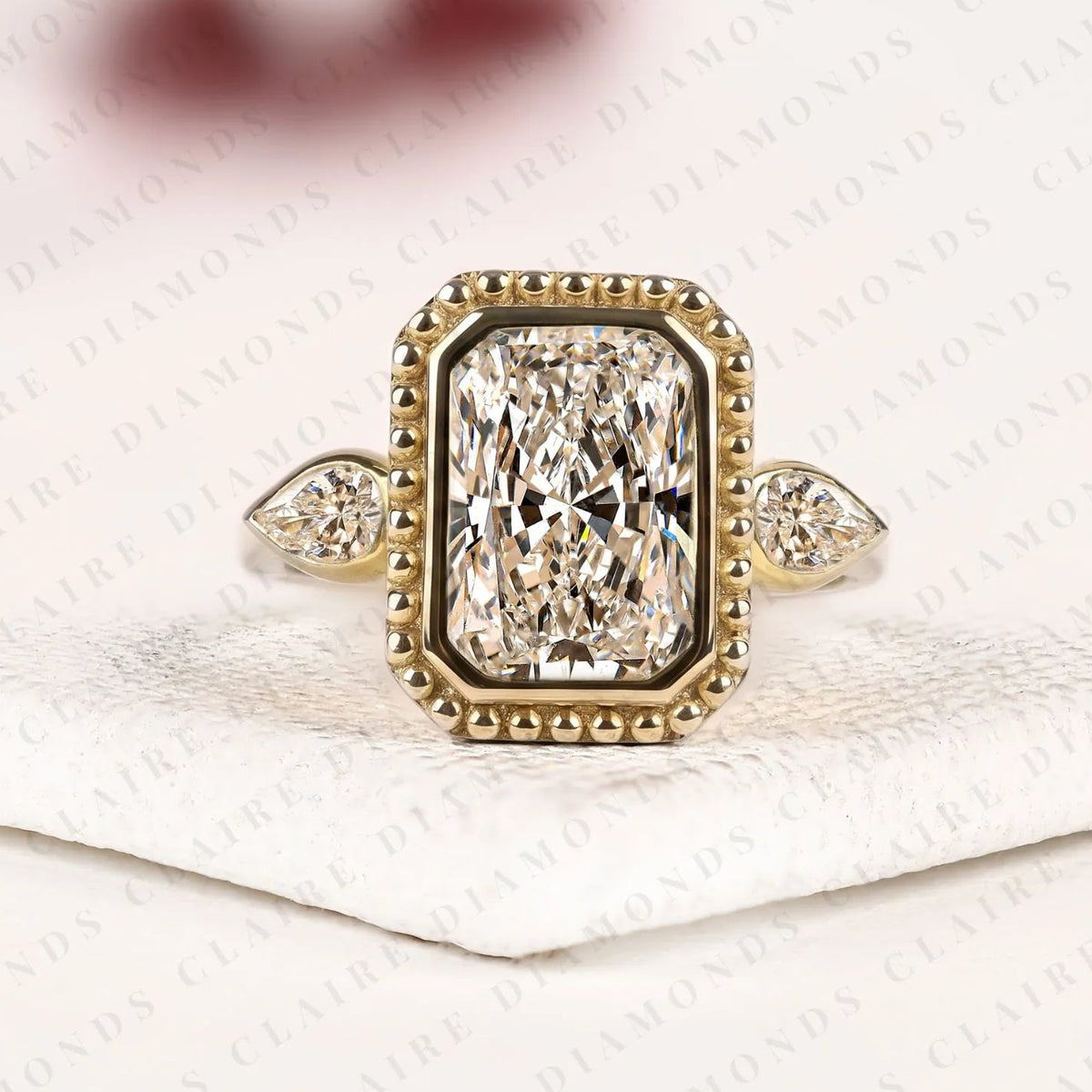 radiant cut lab grown diamond three stone engagement ring | pear cut side stone gold ring | beaded bezel statement bridal jewelry | modern luxury wedding ring