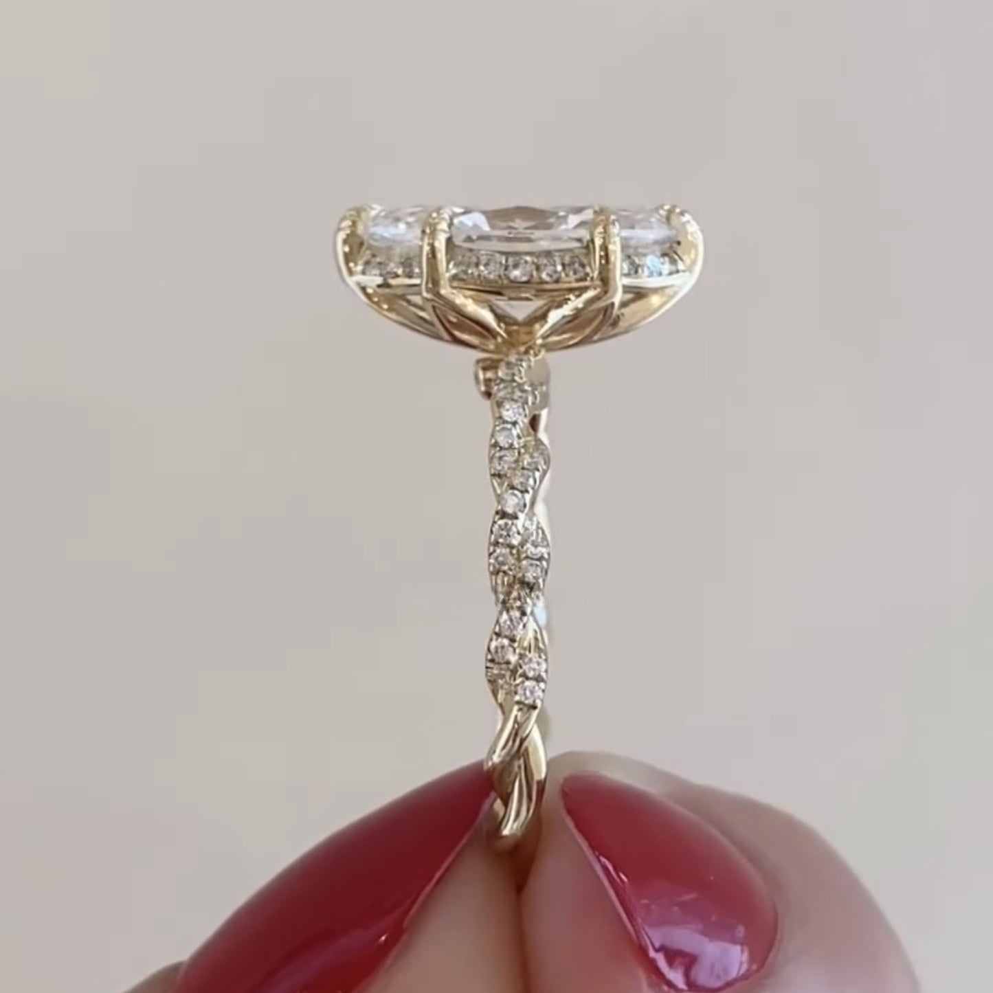 gold ring with diamonds held by a hand against a plain 