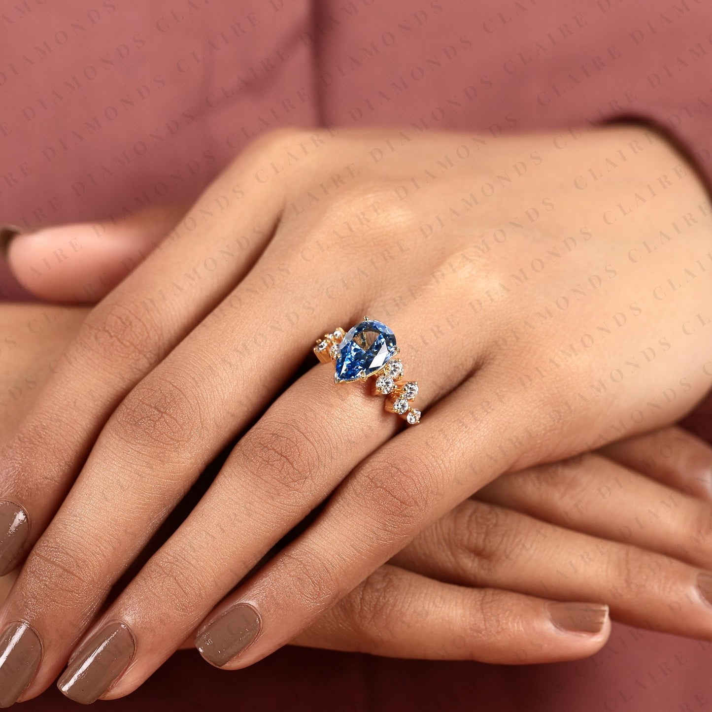 pear cut blue lab grown engagement ring, round diamond floral side stones, yellow gold nature-inspired bridal ring