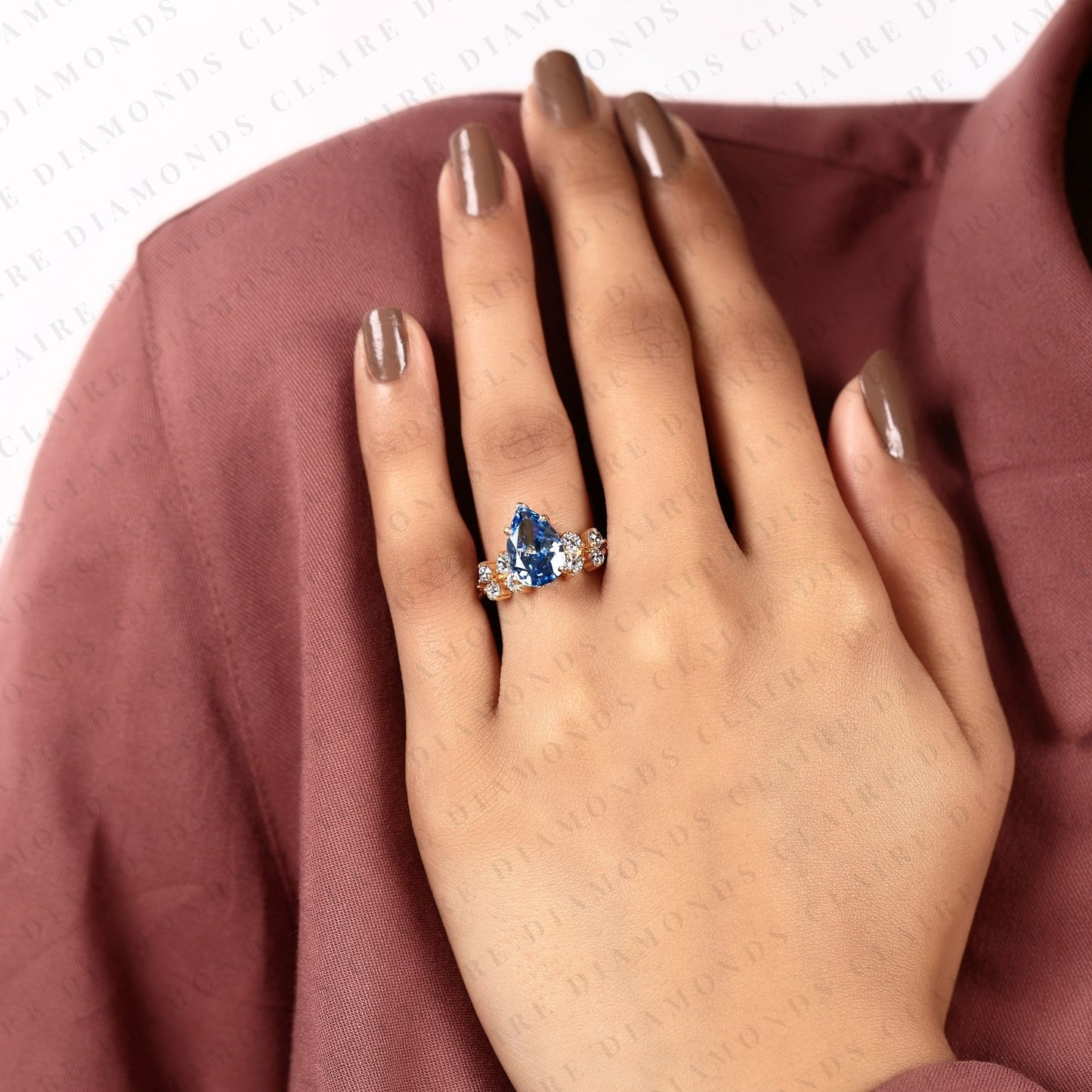 pear cut blue lab grown engagement ring, round diamond floral side stones, yellow gold nature-inspired bridal ring