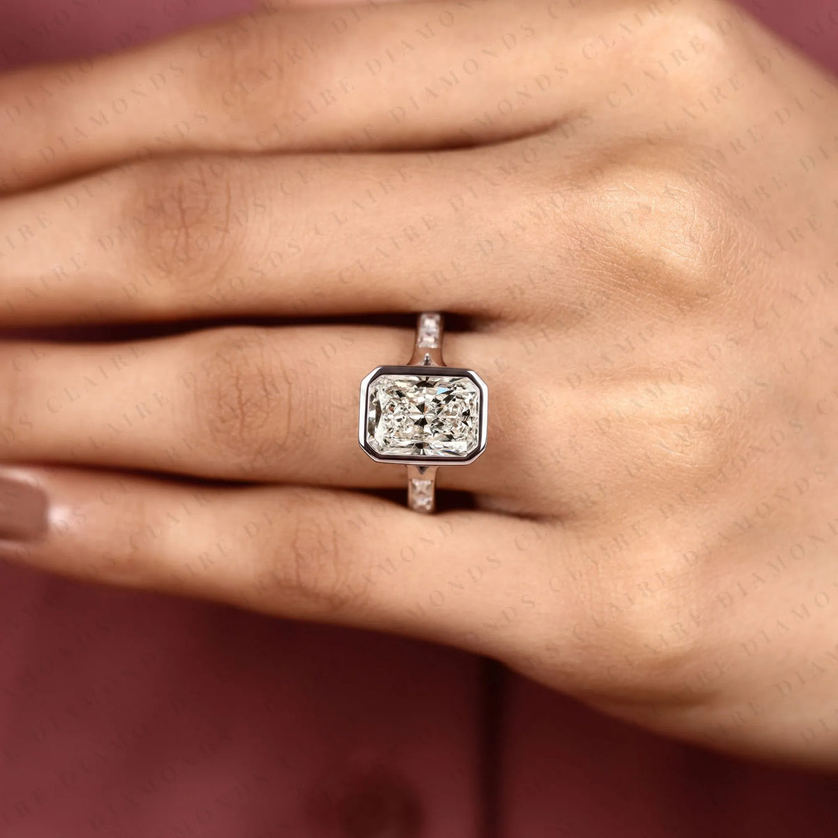 radiant cut moissanite diamond bezel set engagement ring with baguette pave set white gold modern luxury bridal jewelry