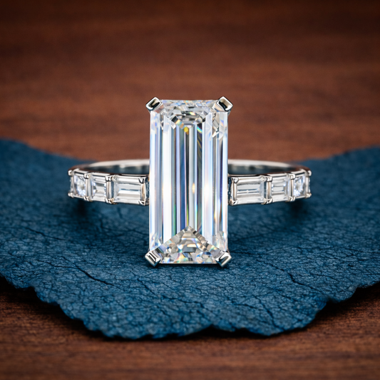 Diamond ring with emerald-cut center stone and baguette side stones on a textured blue and 