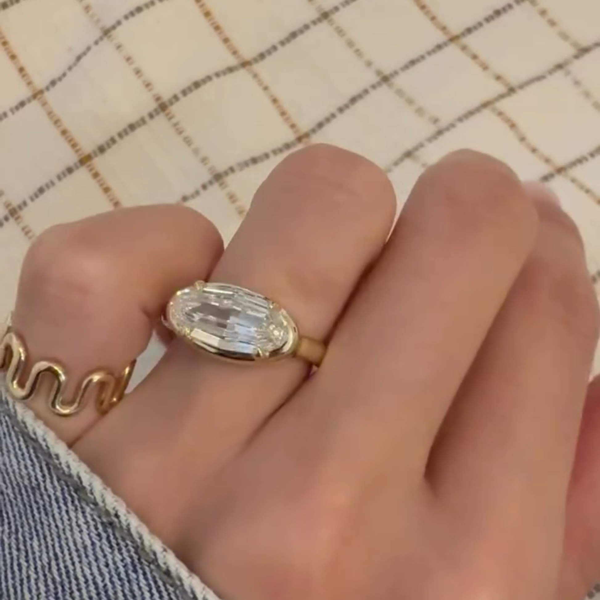 Gold ring with a large diamond on a hand against a checkered