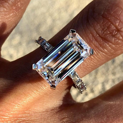 Diamond ring with emerald-cut center stone on a finger