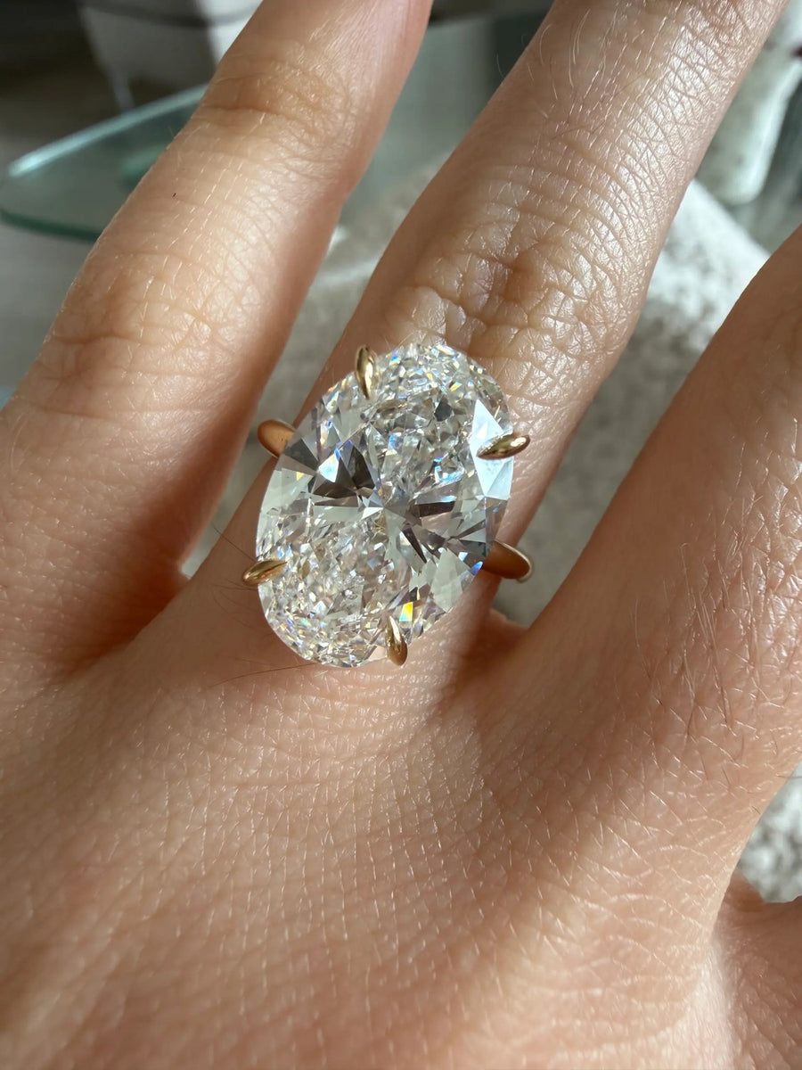 Large oval solitaire engagement ring in yellow gold on a hand