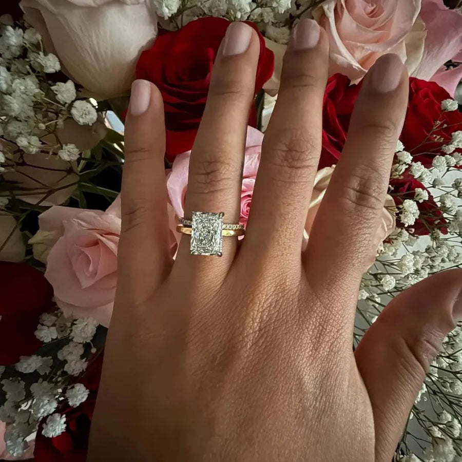 Radiant cut ring with pave band in yellow gold, hand over a bouquet of roses
