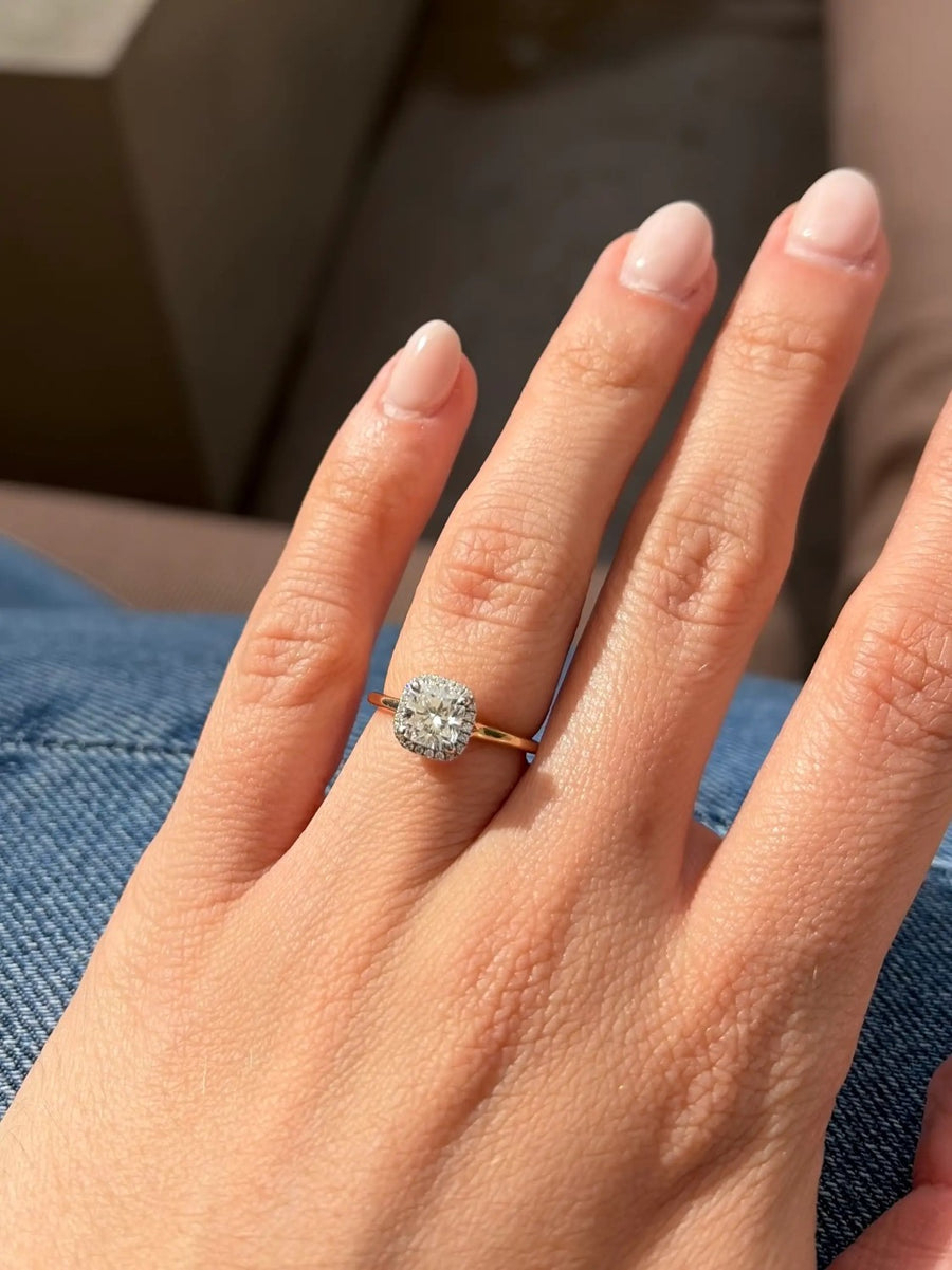 Cushion halo ring on a yellow gold band on a hand