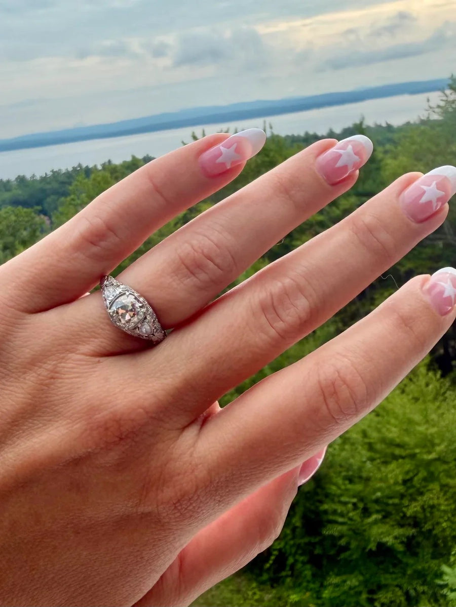Vintage filigree diamond ring against a lake view