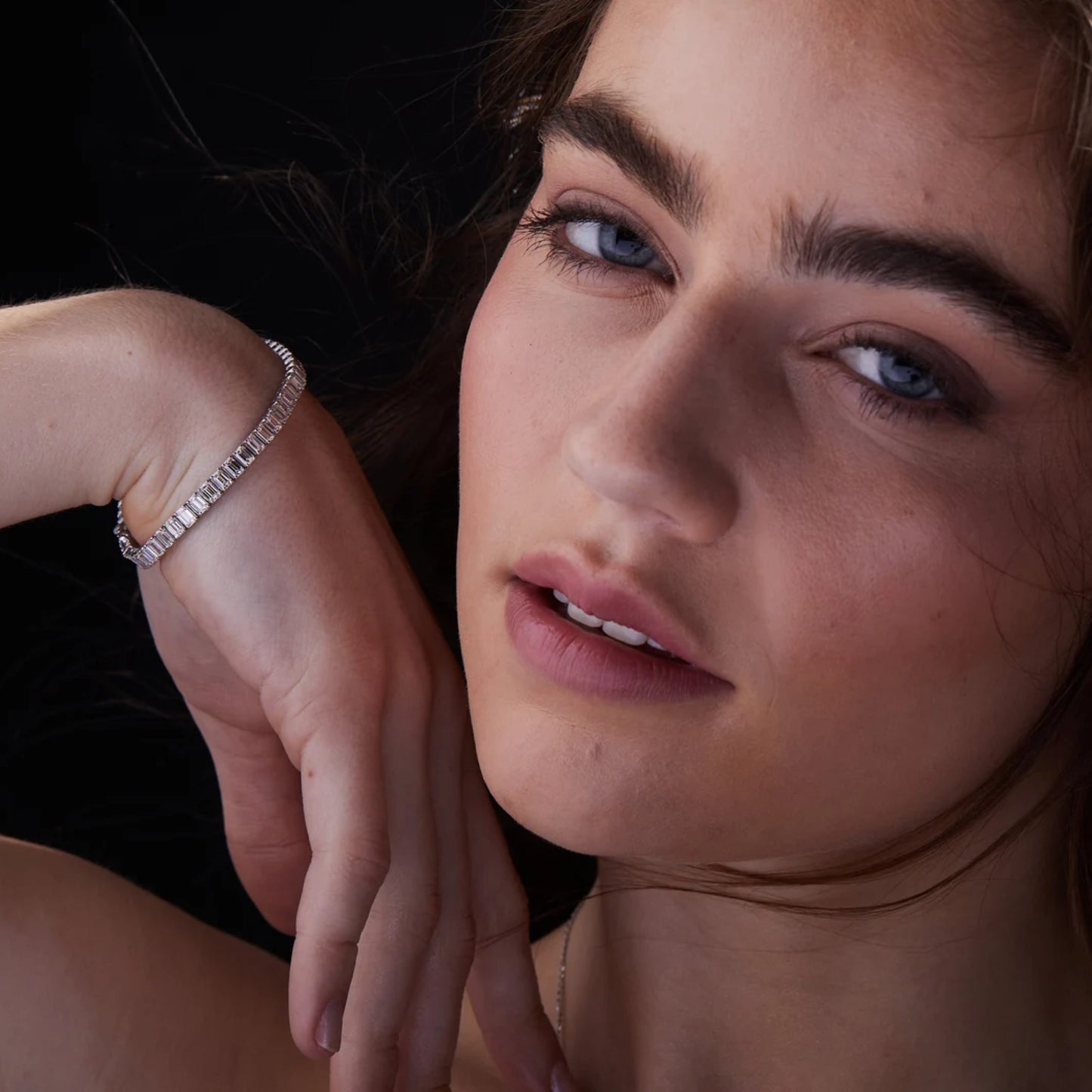 close-up of a woman wearing a diamond bracelet with a dark 