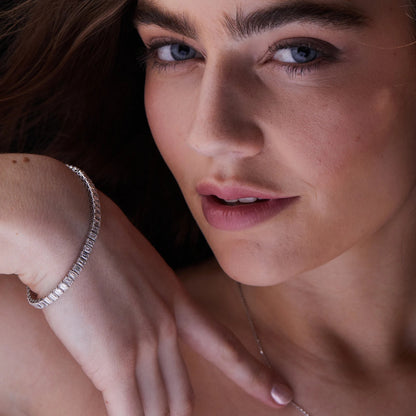 Close-up of a woman's face with a focus on her hand wearing a bracelet.