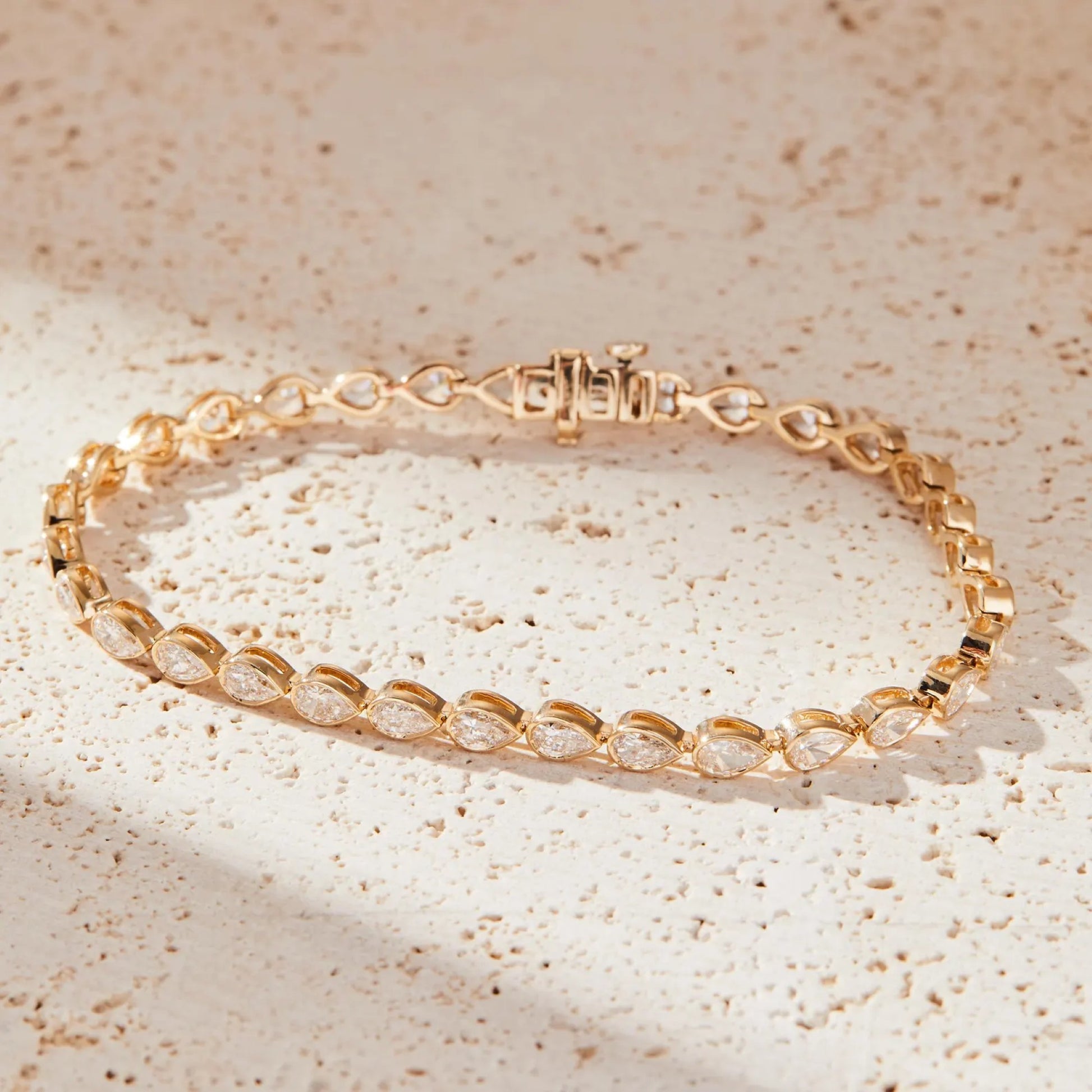 Gold bracelet with clear stones on a beige textured 