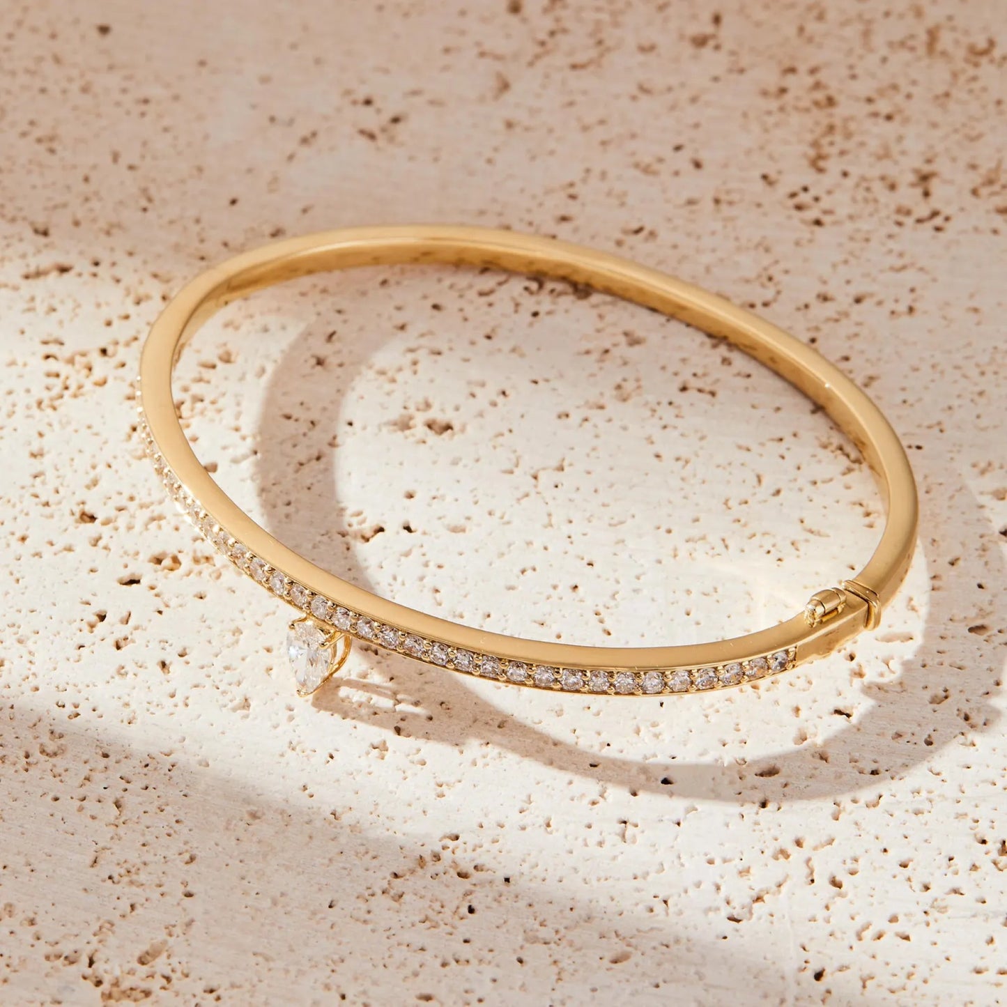 gold bracelet with small diamonds on a textured beige surface