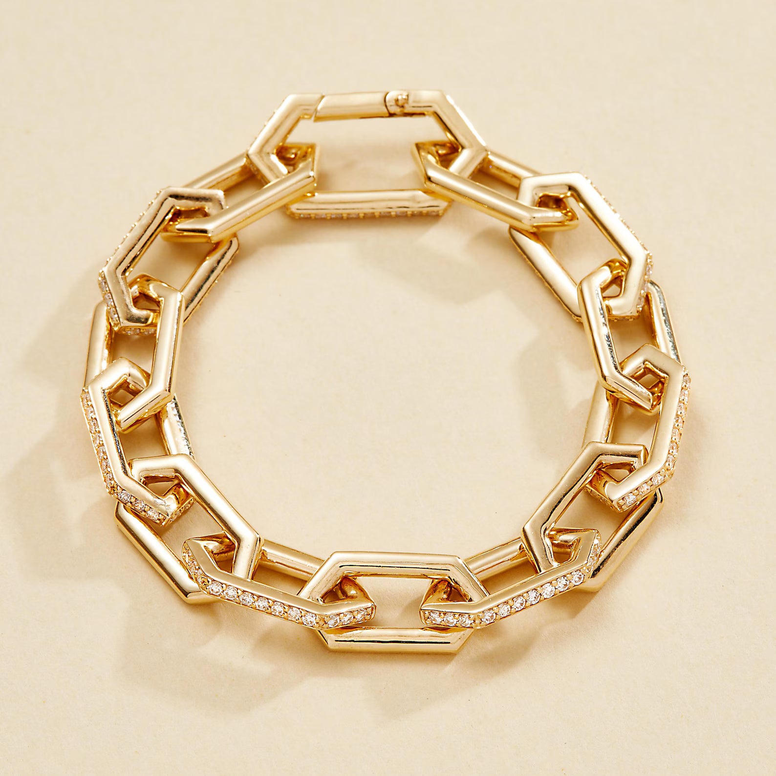 Gold chain bracelet with diamond accents on a beige 