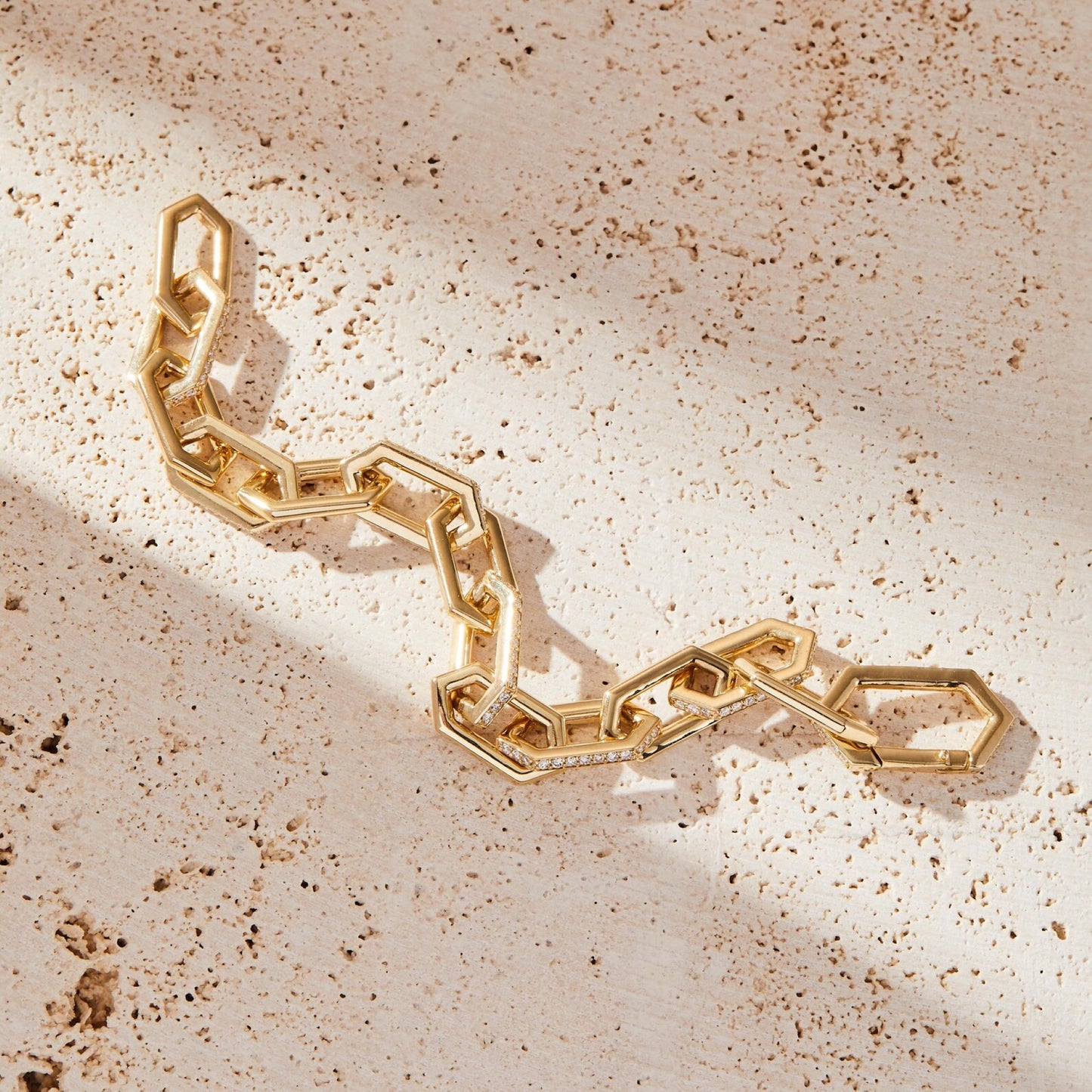 gold bracelet with geometric design on a beige surface