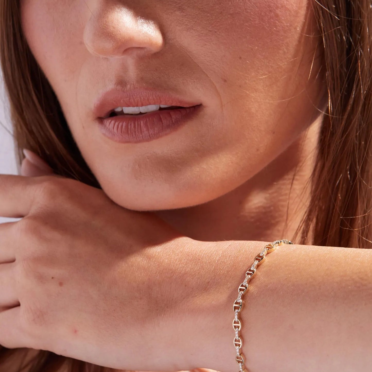 close-up of a woman's face with a gold bracelet on her wrist.