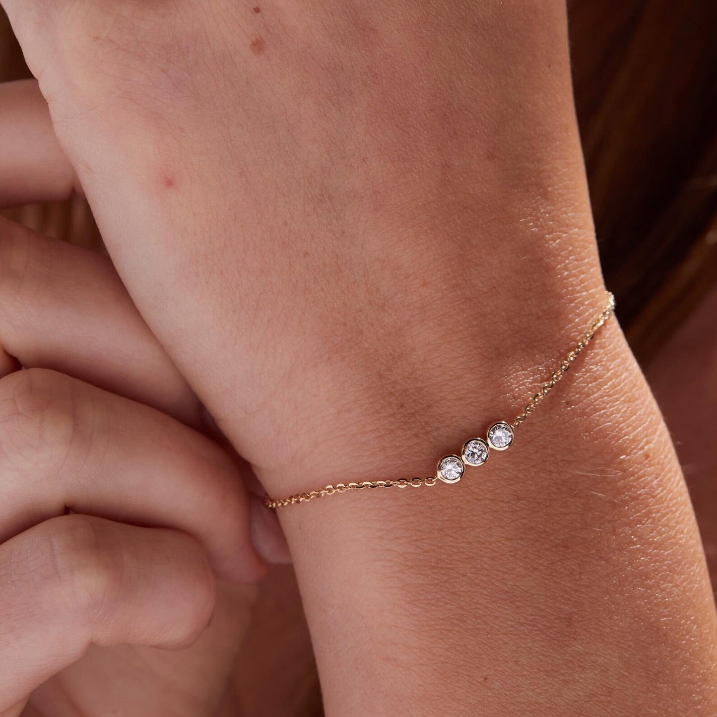 gold bracelet with three clear stones on a wrist