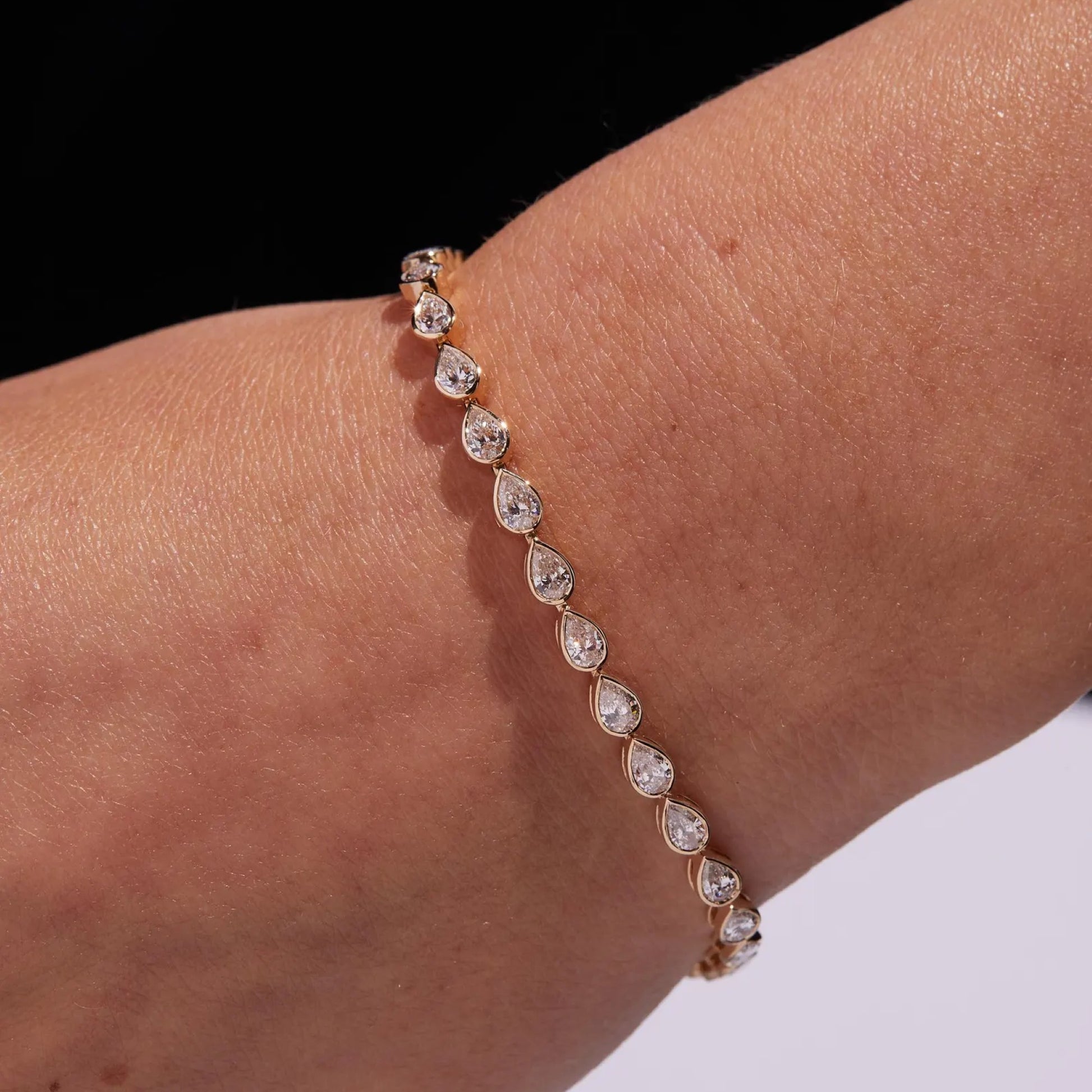 Rose gold bracelet with clear gemstones on a wrist against a black and white 