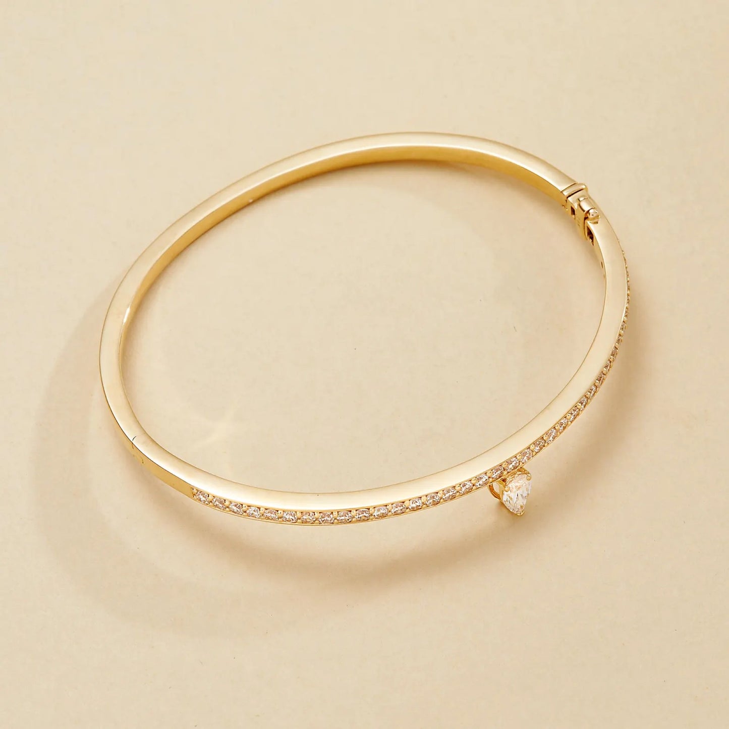 gold bracelet with small diamonds on a beige 