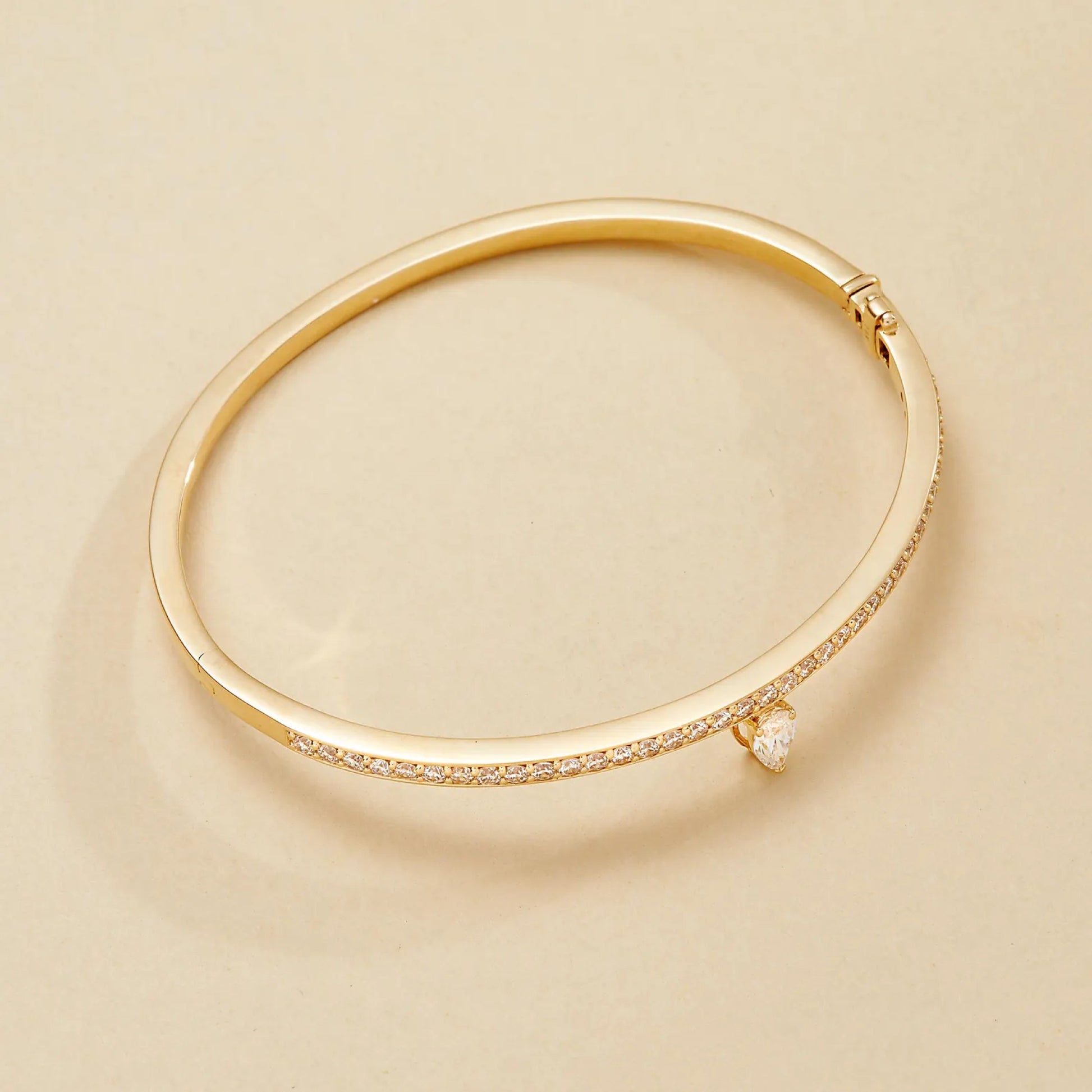 Gold bracelet with small diamonds on a beige 