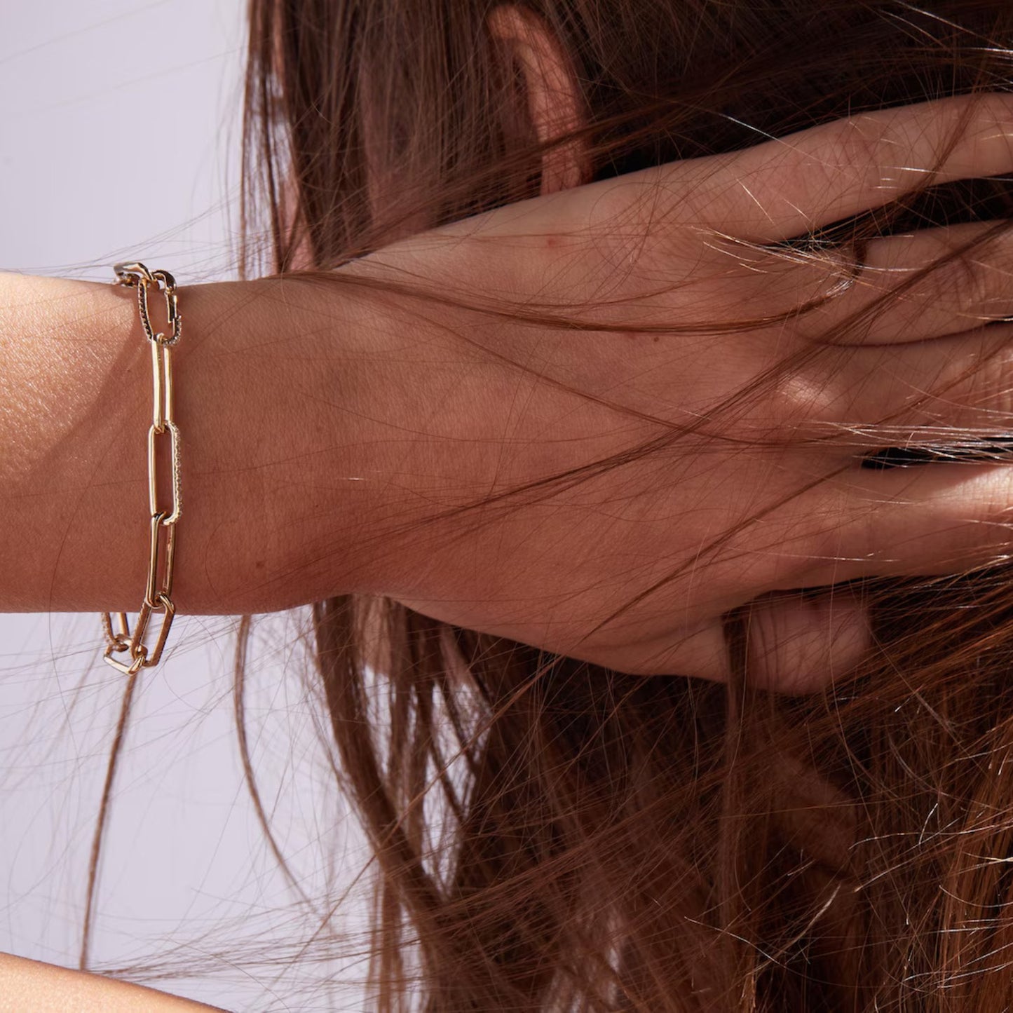 gold chain bracelet on a wrist with hair partially covering it