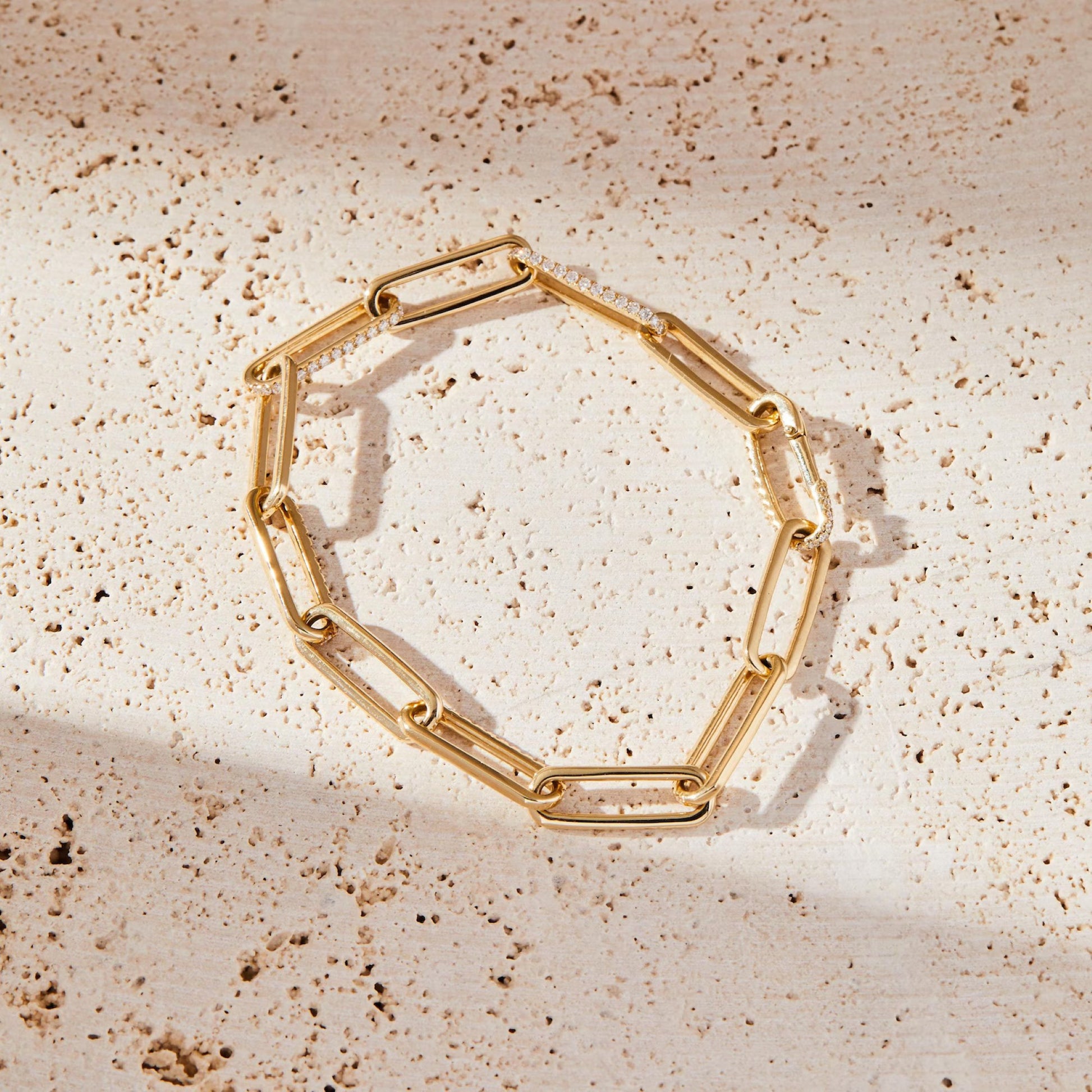Gold chain bracelet on a textured beige surface