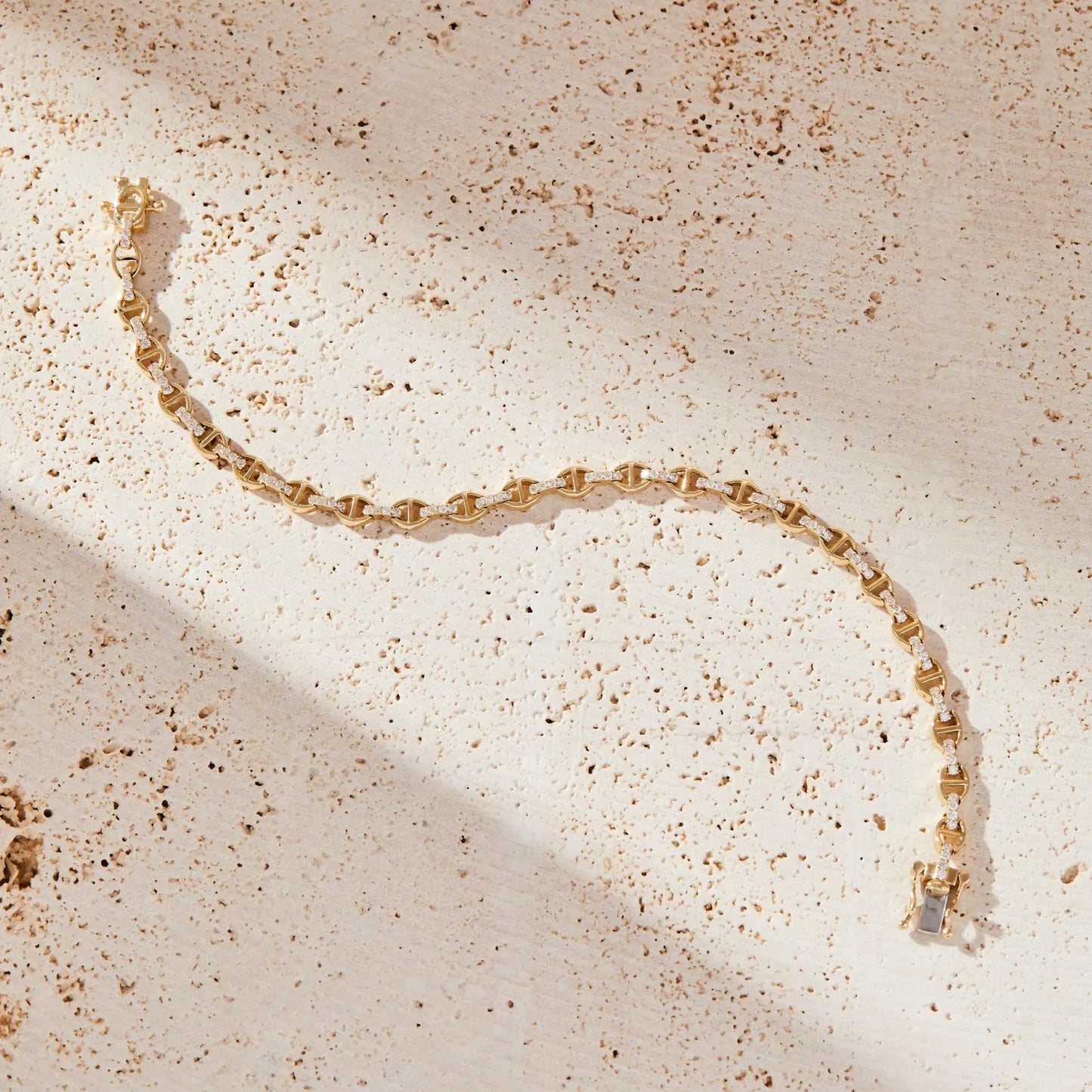 gold bracelet on a textured beige surface