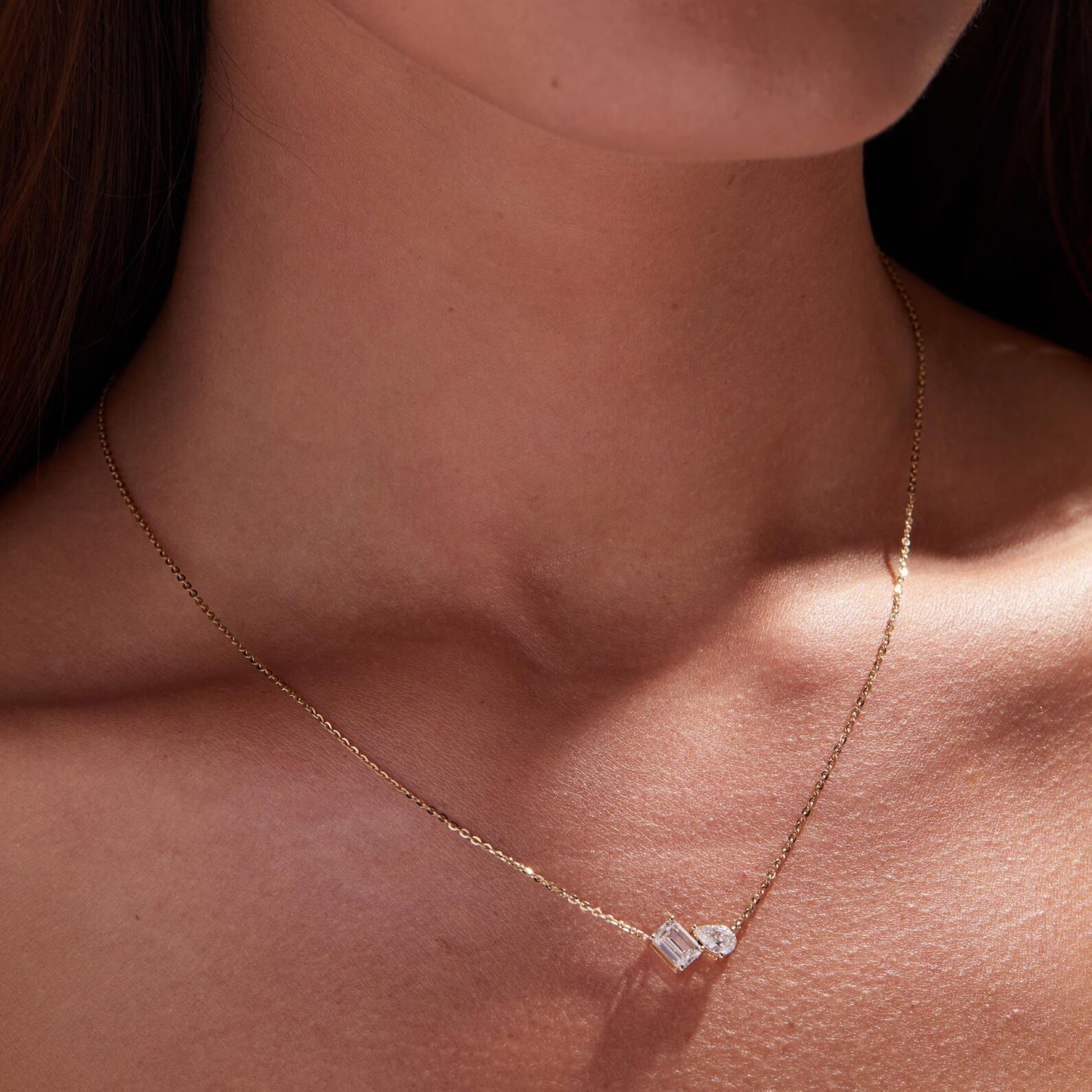 Gold necklace with a diamond pendant on a person's neck