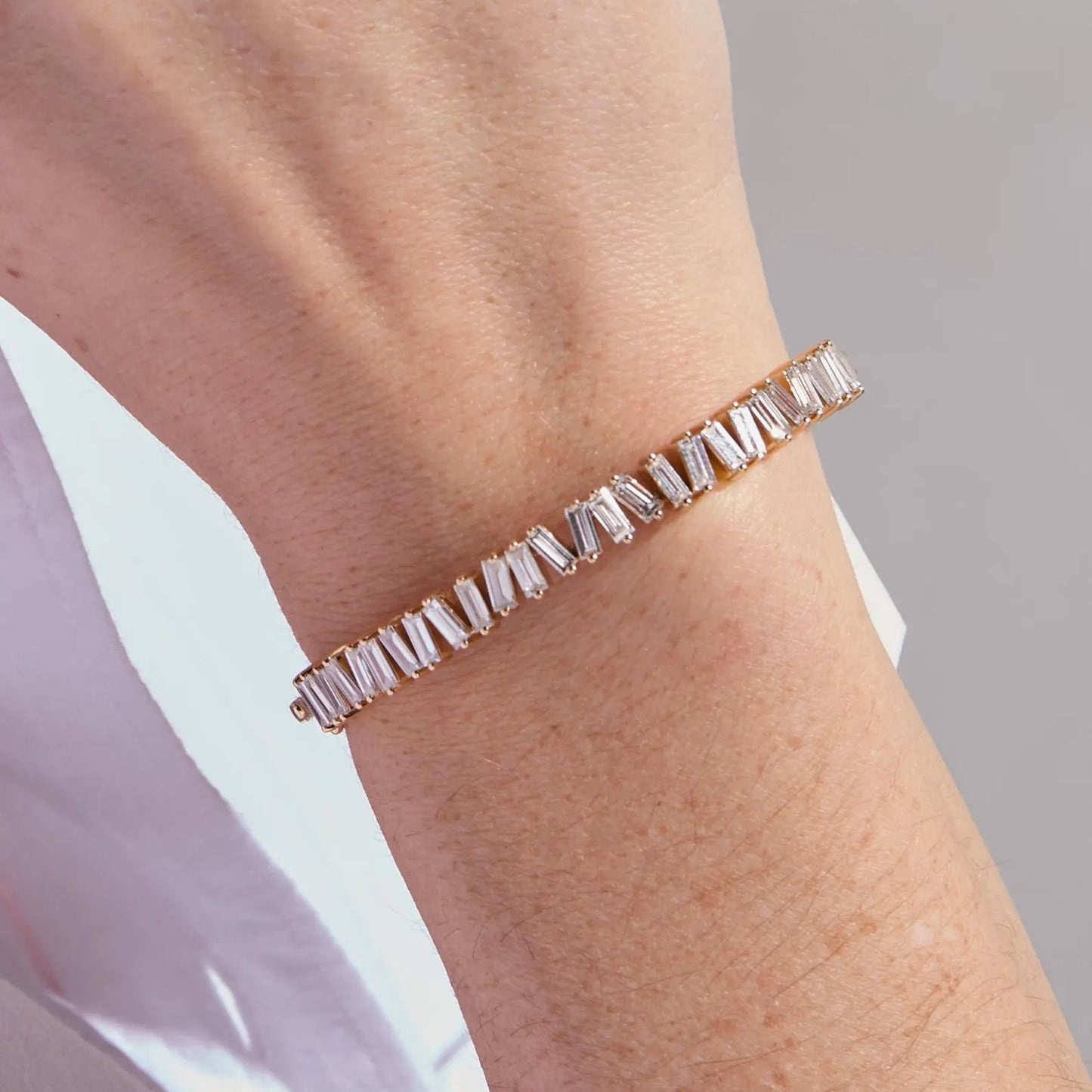 rose gold bracelet with clear stones on a wrist against a neutral background