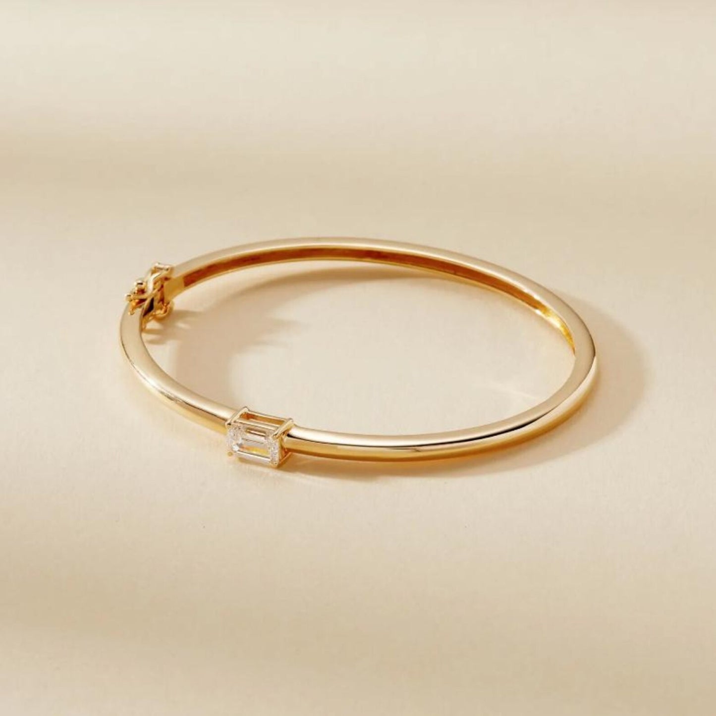 gold bracelet with a diamond on a beige 