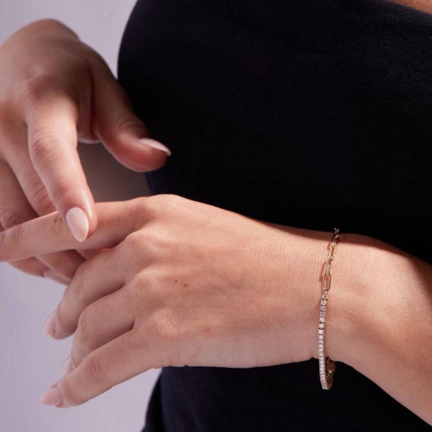 close-up of a person's wrist wearing a delicate bracelet against a neutral 