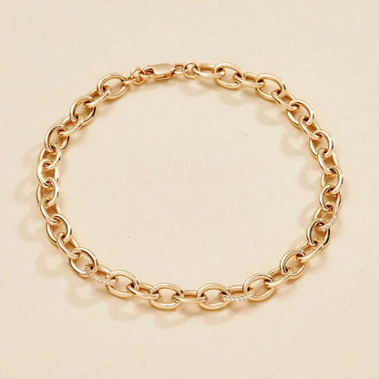 Gold chain bracelet on a beige 