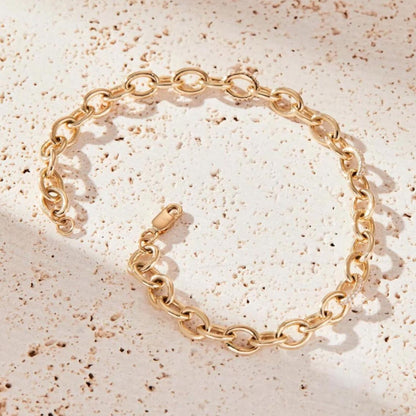 Gold chain bracelet on a textured beige surface