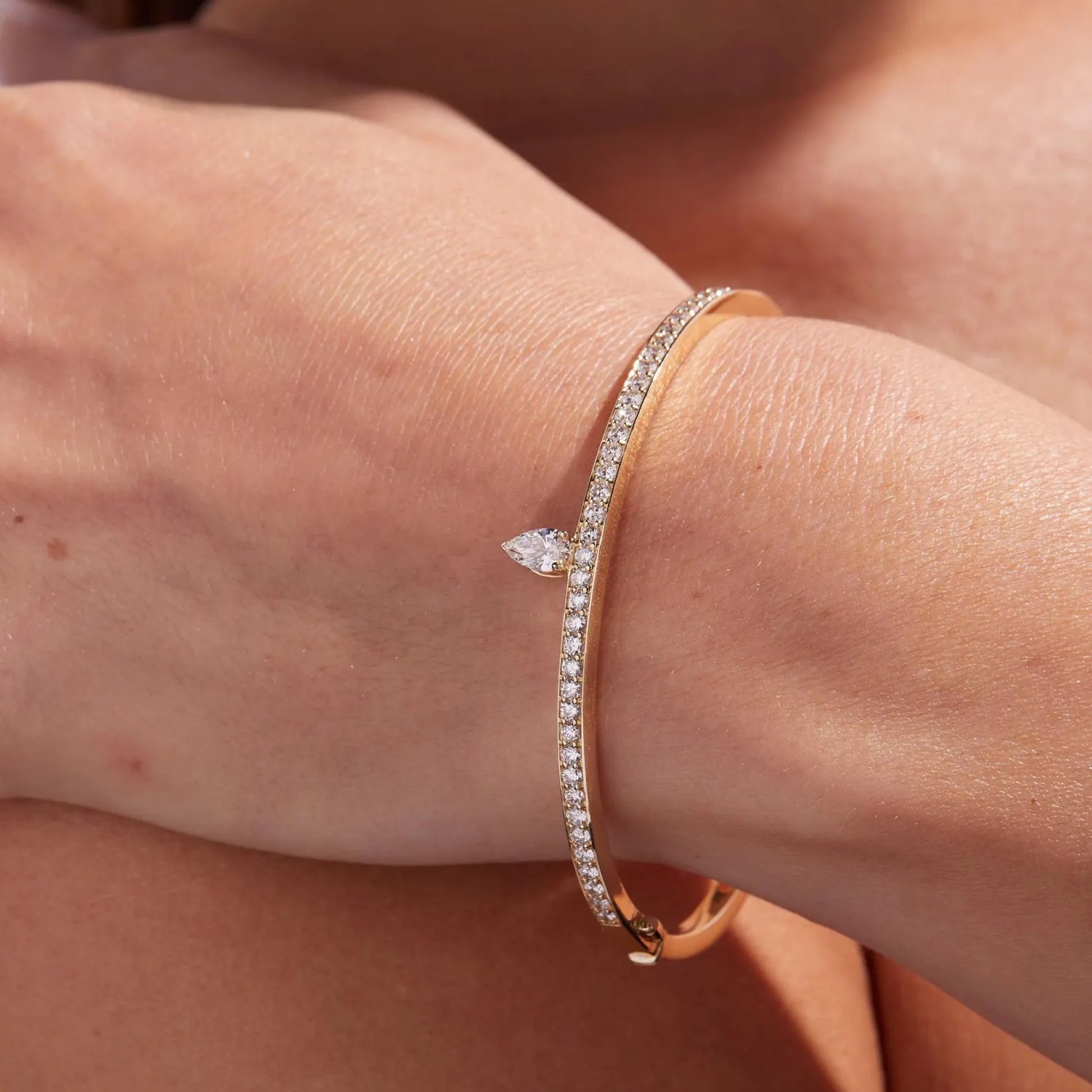 Rose gold bracelet with diamond accents on a wrist against a neutral 