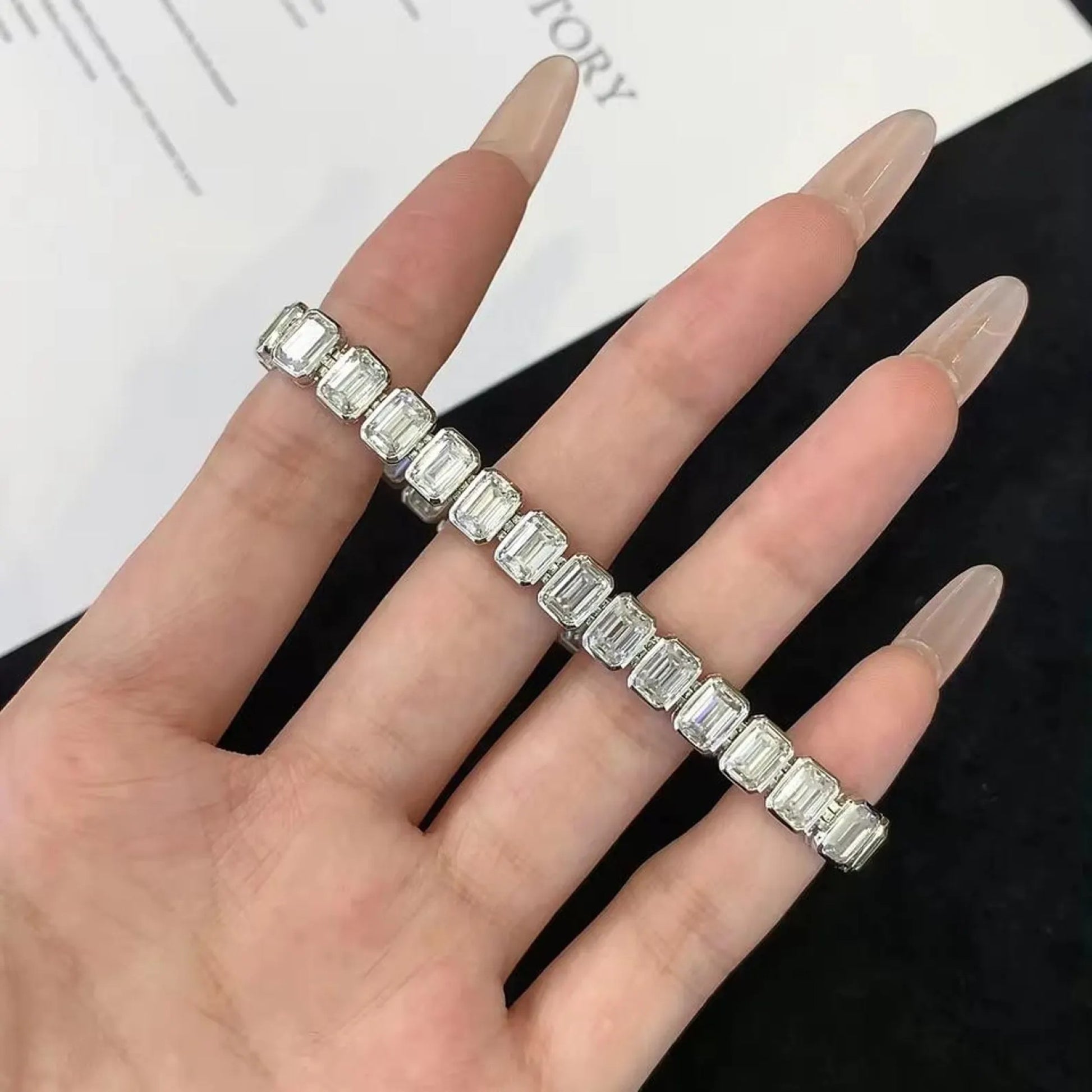 Hand wearing a diamond bracelet on a white 